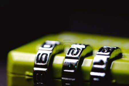 Foto de Una macro toma de un candado verde con un mecanismo de desbloqueo combinado sobre fondo oscuro - Imagen libre de derechos