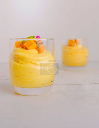 Téléchargez les photos : Un gros plan vertical de puddings à la mangue servis dans des verres sur fond blanc - en image libre de droit
