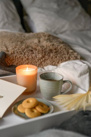 Téléchargez les photos : Composition d'automne confortable avec une tasse de café, bougie, biscuits, cahier, crayon dans un lit confortable - en image libre de droit