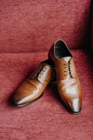 Photo for A vertical shot of the brown elegant shoes on the red couch - Royalty Free Image