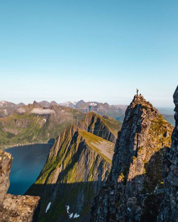 Téléchargez les photos : Un beau cliché d'un randonneur debout sur le sommet de la montagne Husfjellet, île Senja dans le nord de la Norvège - en image libre de droit