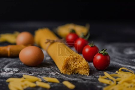 Foto de Un primer plano de pasta cruda sobre una mesa en un restaurante con huevos y tomates cherry alrededor - Imagen libre de derechos