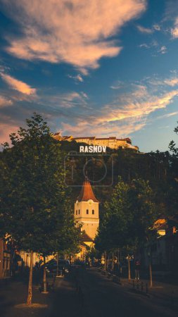 Foto de Un disparo vertical de un cielo al atardecer sobre un acantilado con edificios históricos en Brasov, Rumania - Imagen libre de derechos