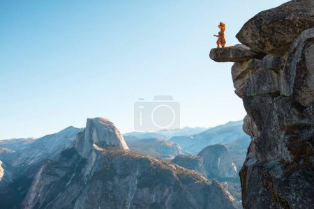 Photo for A person dressed as a dinosaur roaring from the top of a cliff in Glacier point, concept ancient times - Royalty Free Image