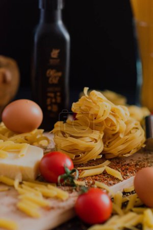 Téléchargez les photos : Un gros plan de pâtes crues sur une table dans un restaurant avec du fromage et des tomates cerises autour - en image libre de droit