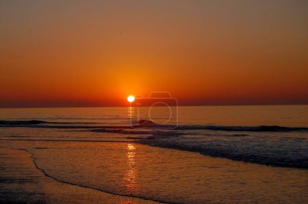 Foto de Una hermosa puesta de sol roja sobre el lago Erie con olas tranquilas - Imagen libre de derechos