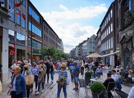 Téléchargez les photos : Une rue bondée avec un café extérieur et des bâtiments traditionnels à Lubeck, en Allemagne, un jour d'été - en image libre de droit