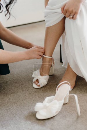 Photo pour Un plan vertical d'une fille aidant la mariée à porter ses chaussures - image libre de droit