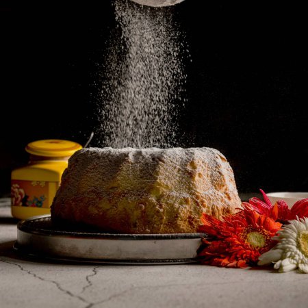 Photo for A closeup of a biscuit with pouring sugar powder served with flowers - Royalty Free Image