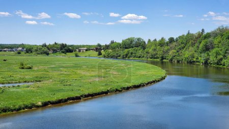 Foto de Un pintoresco plano de un río en un campo verde rodeado de exuberantes árboles en St. Marys Ontario, Canadá - Imagen libre de derechos