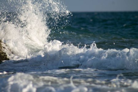Foto de Una vista panorámica de las olas del mar espumosas y estrellarse contra la playa en un día soleado - Imagen libre de derechos