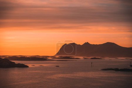 Foto de La puesta de sol dorada en el mar y la silueta de las montañas en el fondo - Imagen libre de derechos