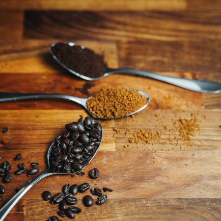 Foto de Un primer plano de granos de café y café molido en cucharas sobre una superficie de madera - Imagen libre de derechos