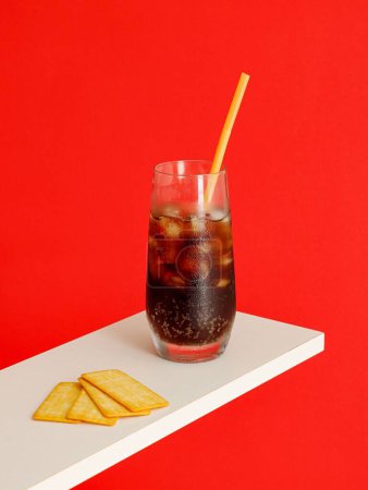 Photo for A Cold carbonated drink with ice cubes and Cracker Biscuit isolated on red background - Royalty Free Image