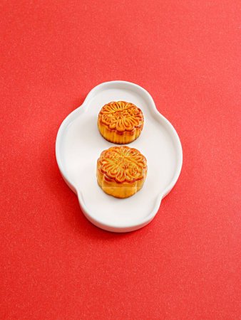 Photo for A vertical shot of mooncakes in a white plate isolated on red background - Royalty Free Image