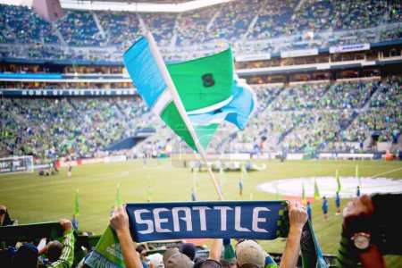Photo for A back view of a fan holding a scarf with SEATTLE writing during Sounders game in the stadium - Royalty Free Image