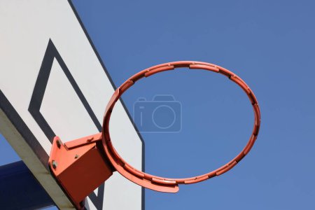 Téléchargez les photos : Gros plan d'un panier de basket sans filet sur fond de ciel bleu - en image libre de droit
