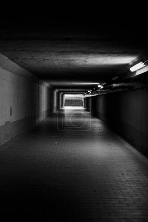 Photo for A grayscale of a dark tunnel with stone floor and lamps n the wall - Royalty Free Image