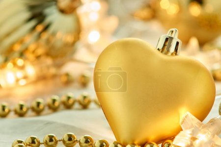 Foto de Un primer plano de adornos de Navidad en forma de corazón dorado colocados en una superficie blanca - Imagen libre de derechos