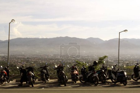 Téléchargez les photos : Une rangée de moteurs dans la rue avec vue sur une ville en Indonésie. - en image libre de droit