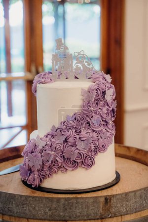 Téléchargez les photos : Un plan vertical d'un gâteau de mariage blanc avec des décorations florales violettes et papillons - en image libre de droit