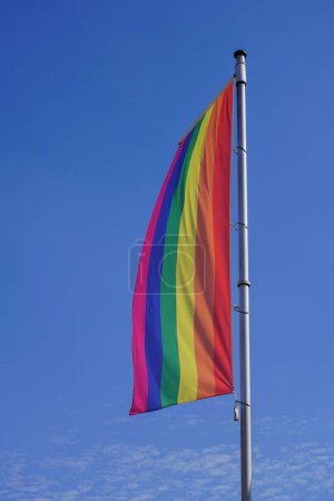 Téléchargez les photos : Un coup vertical de drapeau de fierté sur un pilier contre un ciel bleu - en image libre de droit