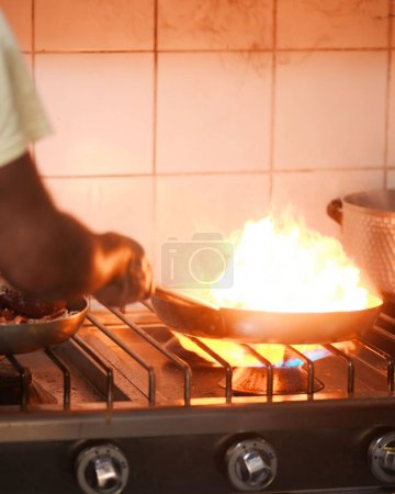Foto de Un disparo vertical de un hombre agarrando una estufa en llamas en la cocina - Imagen libre de derechos