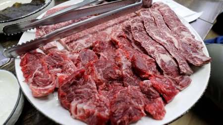 Téléchargez les photos : Un gros plan de viande fraîche tranchée crue disposée dans une assiette blanche - en image libre de droit