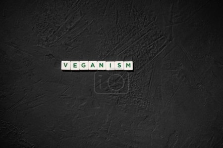 Photo for A set of white cubes with the word veganism on a rough black background - Royalty Free Image