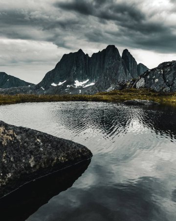 Téléchargez les photos : Vue verticale d'un ciel orageux au-dessus d'une montagne rocheuse et d'un lac dans le nord de la Norvège - en image libre de droit