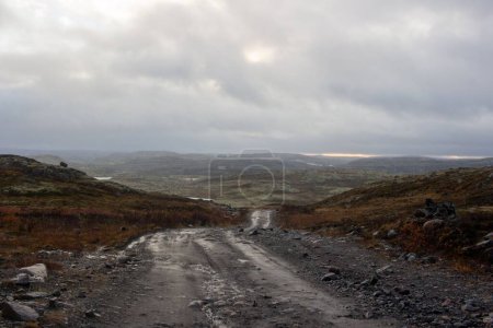 Foto de Un paisaje de un camino rocoso con colinas de cañón bajo el cielo nublado brumoso en el horizonte - Imagen libre de derechos