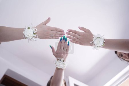 Foto de Las damas de honor en pulseras cogidas de la mano antes de la ceremonia de la boda - Imagen libre de derechos