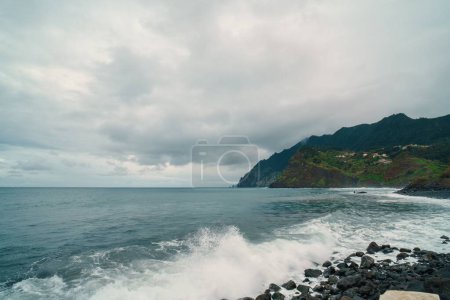 Téléchargez les photos : La vague éclaboussante s'est posée sur la côte rocheuse de la baie de Madère - en image libre de droit