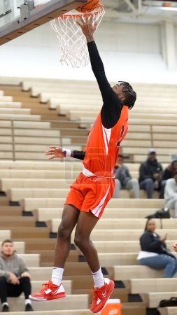 Photo for A vertical shot of a young male player dunking at a fall Merrillville high school basketball game - Royalty Free Image