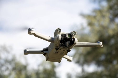 A closeup of DJI Mini 3 Pro aerial drone against the blurred trees background