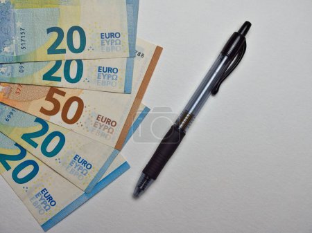 Foto de Billetes de dinero en semicírculo sobre fondo blanco con bolígrafo negro - Imagen libre de derechos