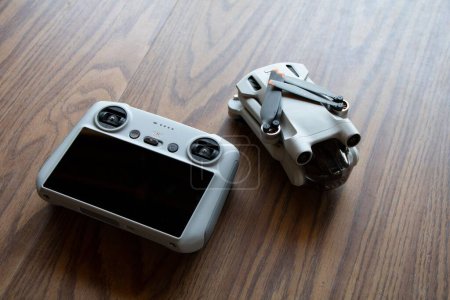 Foto de Un primer plano del dron aéreo DJI Mini 3 Pro y su mando a distancia con pantalla táctil sobre un fondo de madera - Imagen libre de derechos