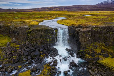 A small waterfall in the Thingvellir National Park under a cloudy sky in Iceland