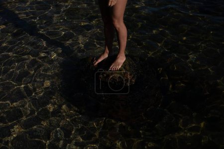Téléchargez les photos : Un gros plan de pieds féminins debout sur la pierre dans l'eau - en image libre de droit