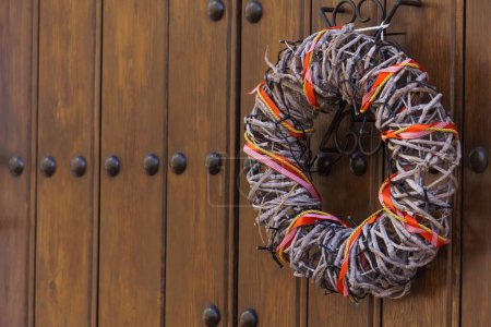 Photo for Wooden door with metal rivets with a colorful wreath as an ornament - Royalty Free Image