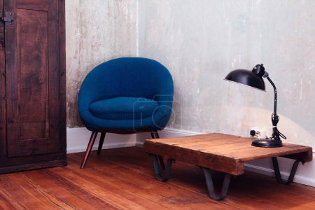 Téléchargez les photos : Un plan intérieur d'un canapé bleu et une table avec une lampe sur un sol en bois. - en image libre de droit