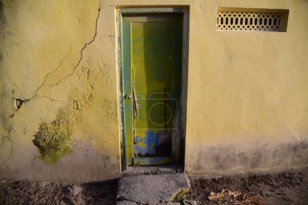 Téléchargez les photos : Gros plan d'une vieille porte rustique et d'un mur fissuré au soleil - en image libre de droit