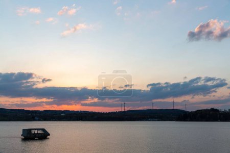 Téléchargez les photos : Une mer avec un bateau au coucher du soleil avec des montagnes en arrière-plan - en image libre de droit