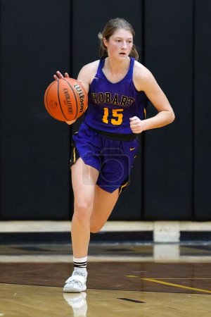 Téléchargez les photos : Un plan vertical d'une jeune joueuse sur un terrain intérieur lors d'un match de basket-ball des filles du lycée - en image libre de droit