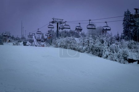 Photo for Ski lift at Poppenberg in the evening. In the tourist area of Winterberg, Germany. Unknown skiers in the lift. - Royalty Free Image