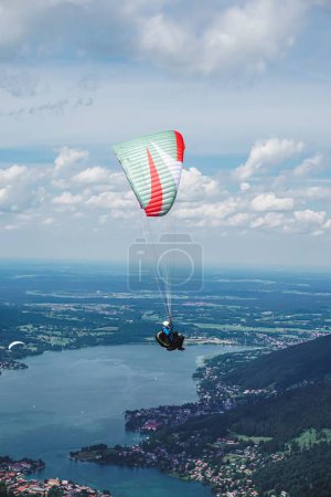 Téléchargez les photos : Plan vertical d'une personne parapente au-dessus d'un lac sous un ciel nuageux bleu - en image libre de droit