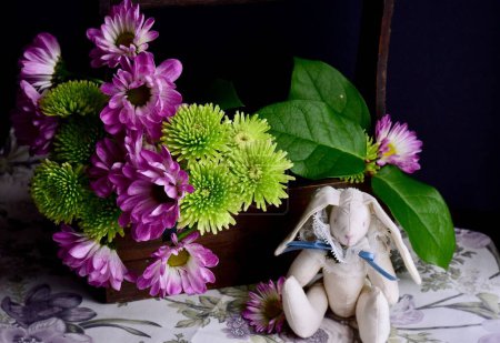 Foto de Una vista de cerca de las flores de primavera y un conejito de peluche en un mantel floral - Imagen libre de derechos