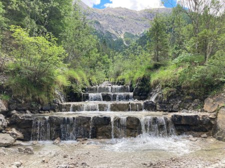 Téléchargez les photos : Un beau paysage d'une cascade artificielle au milieu de montagnes boisées - en image libre de droit