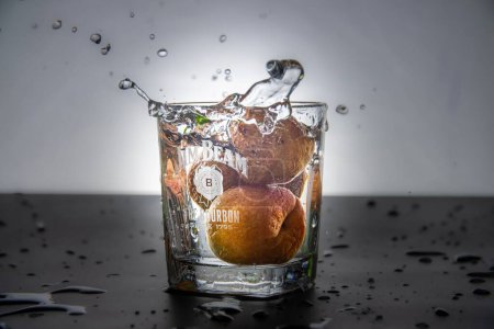 Photo for Two apricots splashing in a Jim Beam glass - Royalty Free Image