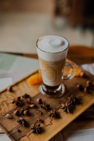 Foto de Un primer plano de un latte en capas en un vaso alto sobre una tabla de madera en un café - Imagen libre de derechos